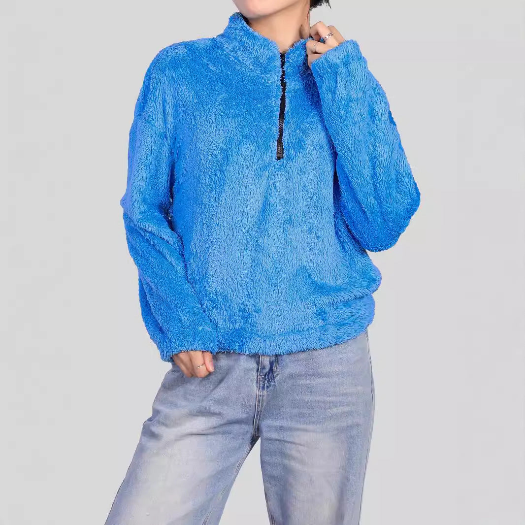 Donna con maglione blu in pile, zip frontale, indossa jeans chiari. Moda casual autunnale, abbigliamento caldo e confortevole.