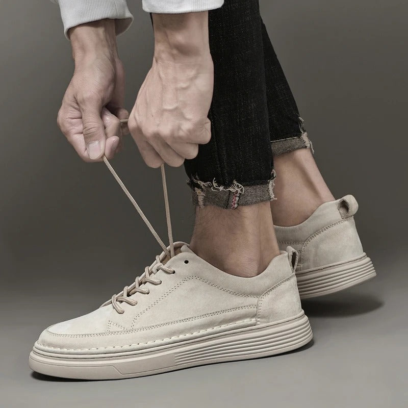 Scarpe da ginnastica beige in pelle scamosciata, uomo allaccia i lacci, jeans neri arrotolati, moda casual, calzature eleganti, tendenze 2023.