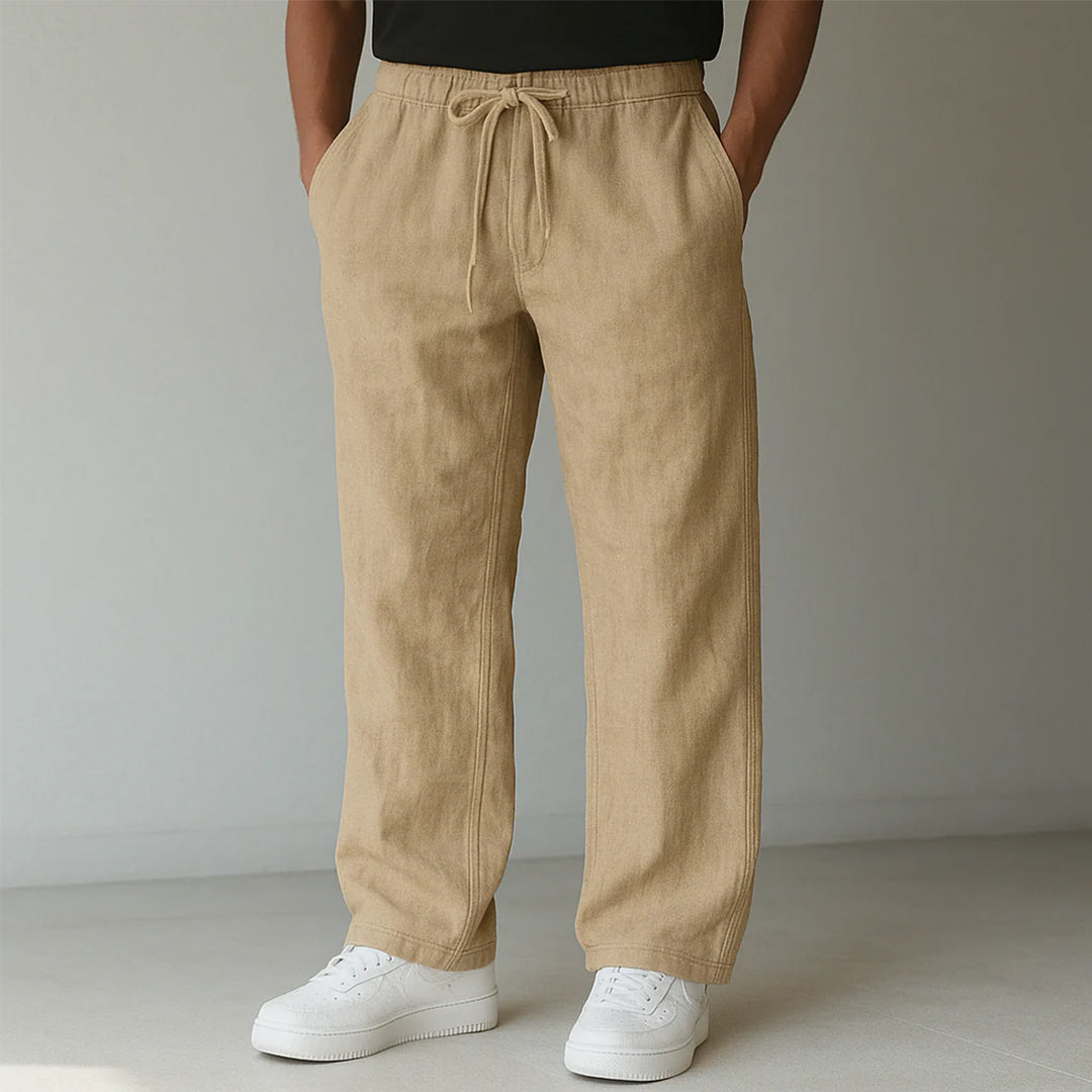 Pantaloni beige in lino con coulisse, indossati con scarpe da ginnastica bianche. Moda casual uomo, abbigliamento estivo, stile rilassato.