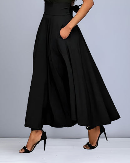 Donna in abito lungo nero elegante, con tasche, indossa tacchi alti neri. Moda femminile, abbigliamento da sera, stile sofisticato.