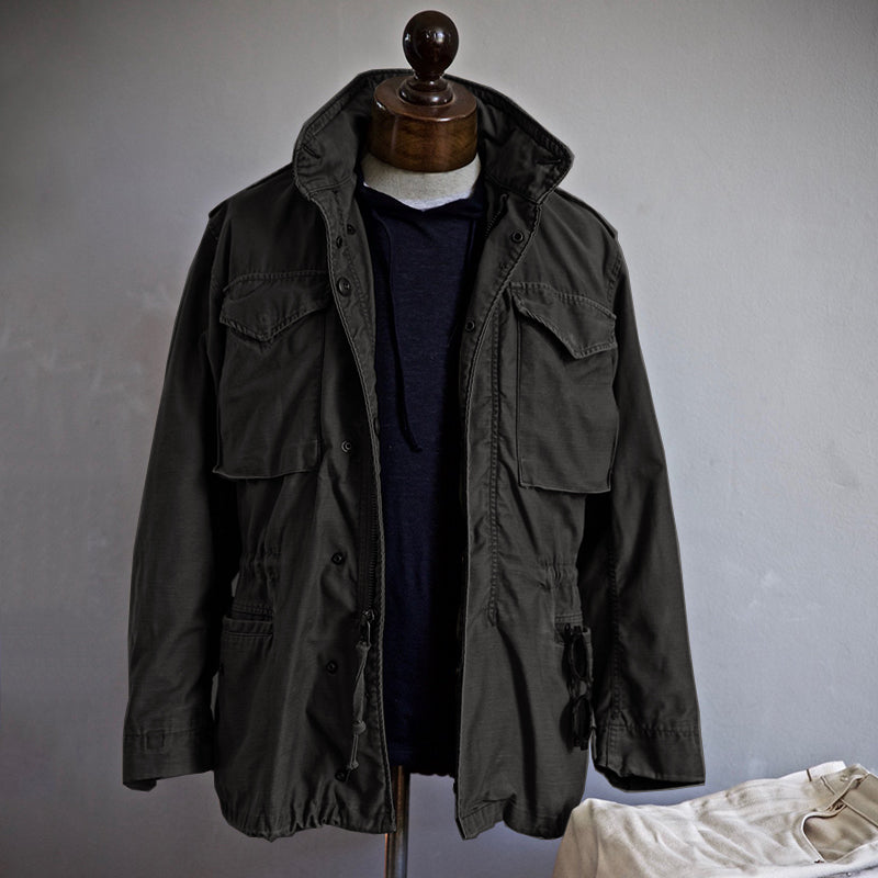 Giacca militare verde oliva su manichino, stile casual, con tasche frontali e cappuccio. Moda uomo, abbigliamento autunnale, giacca utility.
