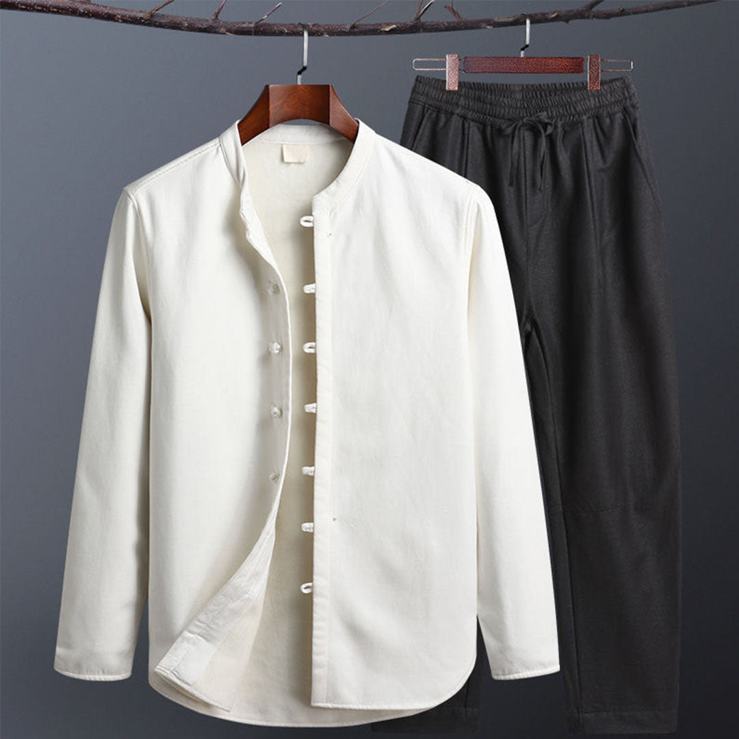 Camicia bianca in cotone con colletto alla coreana e pantaloni neri appesi su gruccia. Abbigliamento casual elegante, moda uomo.