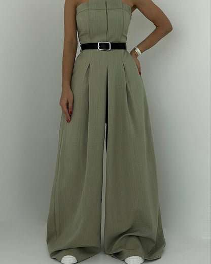 Donna in elegante tuta verde oliva con cintura nera, pantaloni a palazzo e scarpe bianche. Moda femminile, abbigliamento chic, stile contemporaneo.