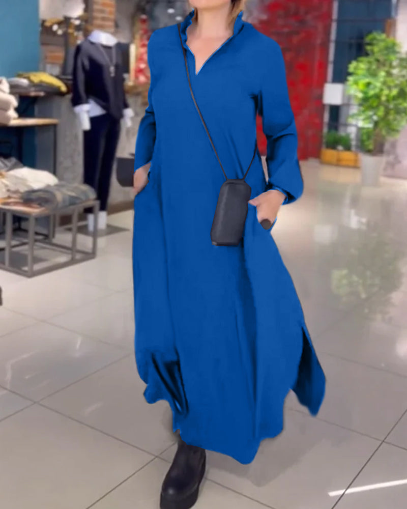 Donna in abito lungo blu con tasche, borsa a tracolla nera, stivali neri, in negozio di moda. Abbigliamento casual elegante, shopping.