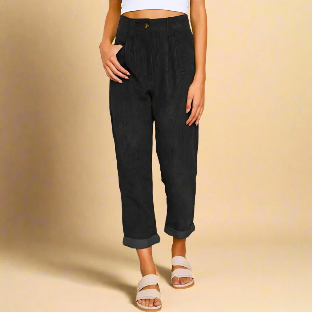 Pantaloni neri a vita alta, stile casual, con risvolto, indossati da una donna in sandali bianchi. Moda femminile, abbigliamento trendy.