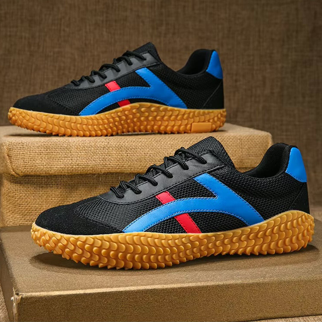 Scarpe sportive nere con dettagli blu e rossi, suola in gomma gialla, esposte su scatole di cartone. Design moderno e casual per uomo.