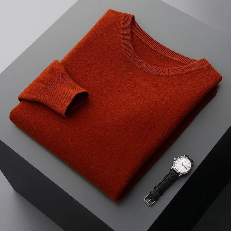 Maglione arancione piegato su tavolo grigio con orologio da polso nero e quadrante bianco. Moda autunnale, abbigliamento elegante, accessori uomo.
