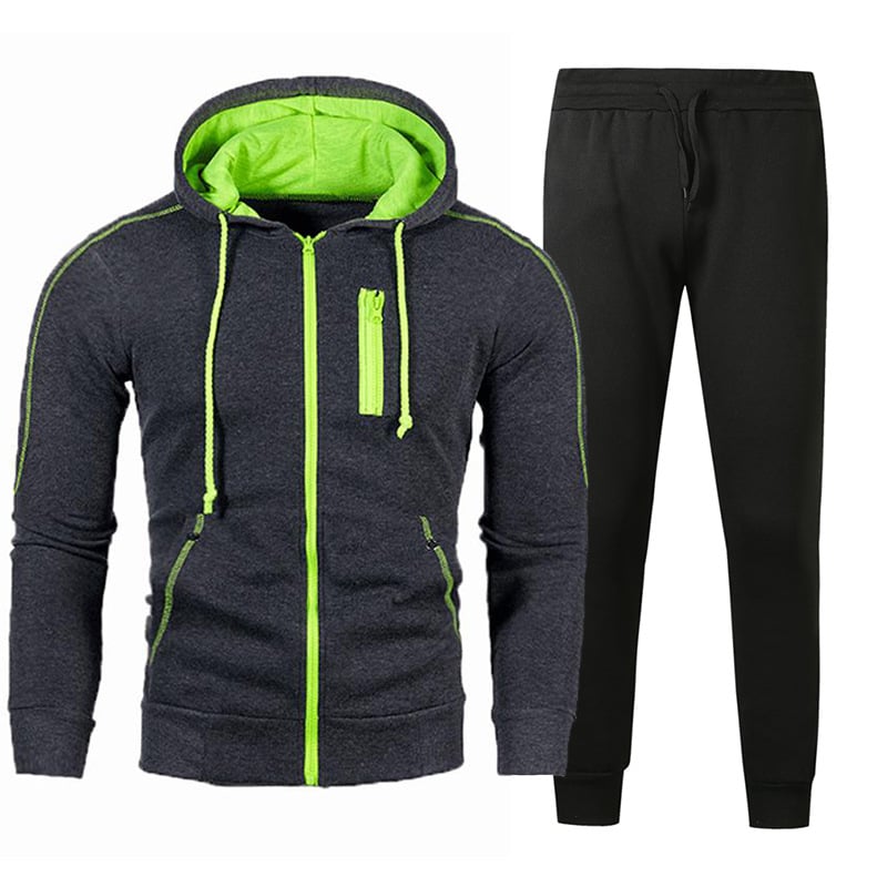 Tuta sportiva uomo, felpa con cappuccio grigio scuro e dettagli verdi, pantaloni neri. Abbigliamento casual, moda fitness, stile moderno.