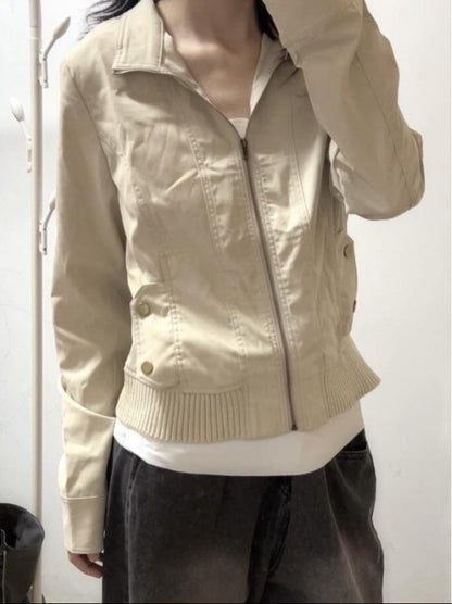 Giacca beige da donna con cerniera, stile casual, indossata sopra una maglietta bianca. Moda autunnale, abbigliamento femminile trendy.