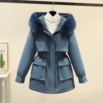 Giacca invernale blu con cappuccio in pelliccia sintetica, tasche frontali e chiusura a zip, appesa su gruccia. Elegante e calda per la stagione fredda.