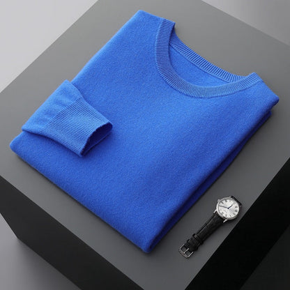 Maglione blu piegato su tavolo grigio accanto a orologio da polso elegante. Moda uomo, abbigliamento invernale, accessori di lusso.