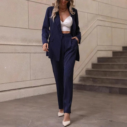 Donna in abito gessato blu scuro, top bianco, tacchi beige, posa su scala urbana. Moda elegante, stile business casual, tendenze abbigliamento femminile.