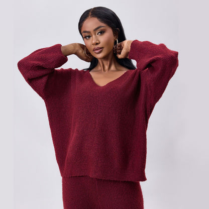 Donna con maglione rosso bordeaux, posa elegante, moda autunno inverno, abbigliamento femminile, stile casual chic, sfondo grigio chiaro.