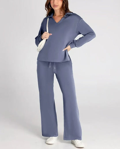 Donna in tuta sportiva blu, con felpa e pantaloni larghi, borsa bianca a tracolla, scarpe da ginnastica bianche. Moda casual donna.