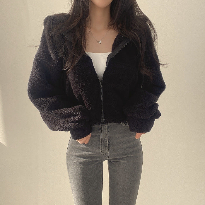 Donna con giacca in pile nero, top bianco e jeans grigi. Moda casual autunnale, abbigliamento femminile trendy, stile urbano.