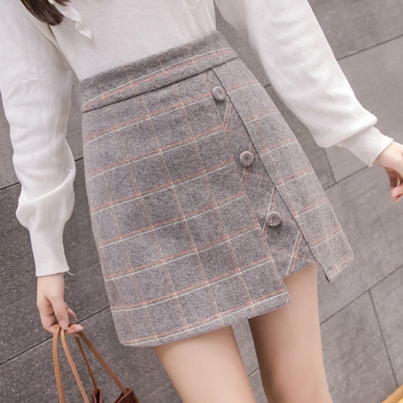 Gonna a quadri grigia con bottoni, indossata con maglione bianco. Moda autunnale, stile casual chic, tessuto caldo, outfit femminile elegante.