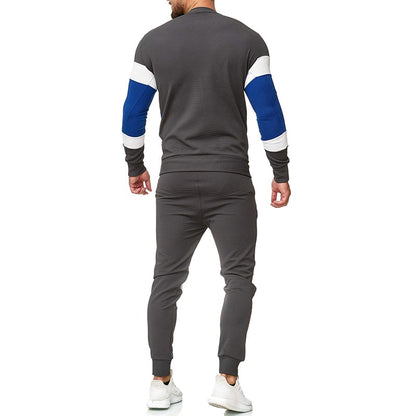 Uomo in tuta sportiva grigia con dettagli blu e bianchi, vista posteriore. Indossa scarpe da ginnastica bianche. Abbigliamento casual maschile.