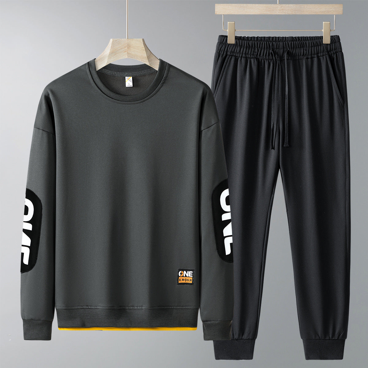 Completo tuta sportiva uomo grigio scuro, felpa e pantaloni con scritta "ONE" sulle maniche. Abbigliamento casual, moda uomo, stile urbano.