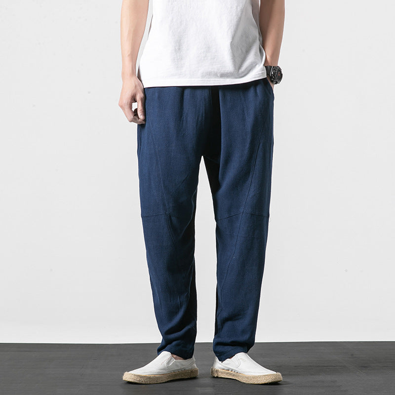 Uomo in piedi indossa pantaloni larghi blu scuro, maglietta bianca e scarpe casual bianche. Moda maschile casual, abbigliamento estivo.