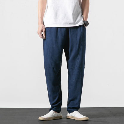 Uomo in piedi indossa pantaloni larghi blu scuro, maglietta bianca e scarpe casual bianche. Moda maschile casual, abbigliamento estivo.