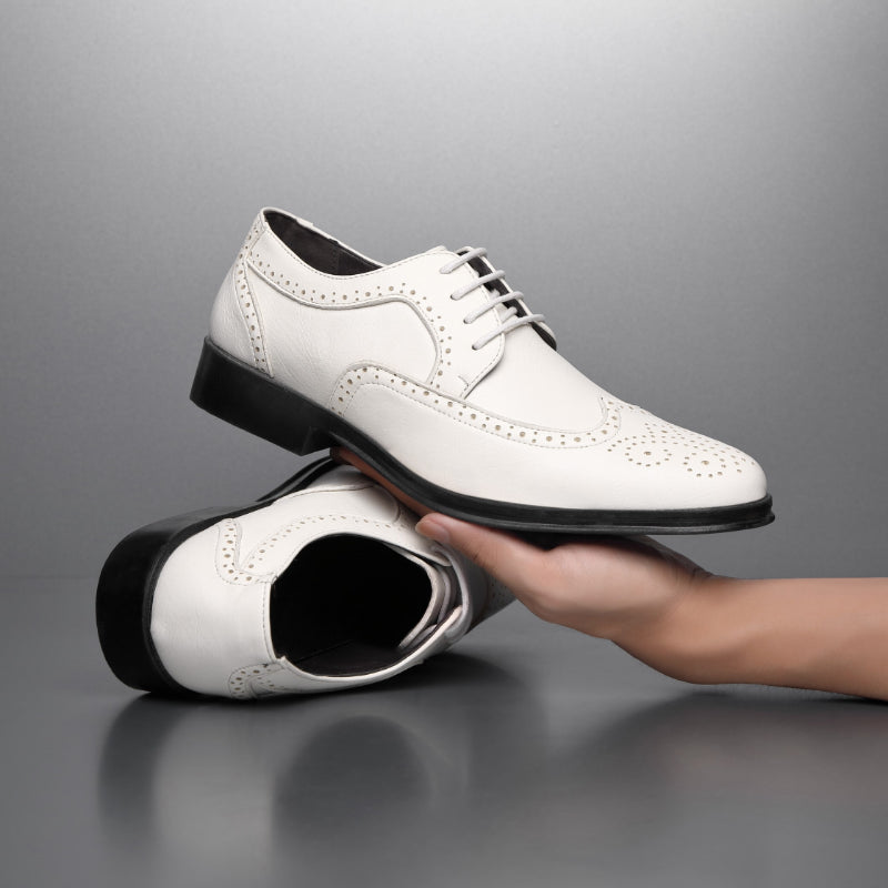 Scarpe eleganti bianche da uomo in pelle, stile brogue, con suola nera, su sfondo grigio. Calzature formali di lusso, moda maschile.