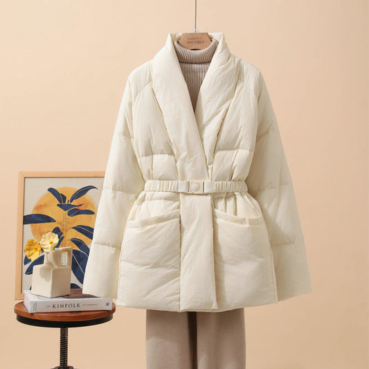 Giacca imbottita bianca elegante su sfondo beige, con cintura in vita. Perfetta per l'inverno, moda donna, abbigliamento caldo e confortevole.