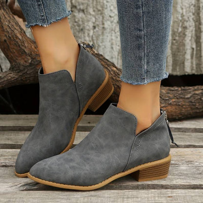 Stivaletti grigi in pelle scamosciata con tacco basso, indossati con jeans. Scarpe moda donna, stile casual, perfette per l'autunno.