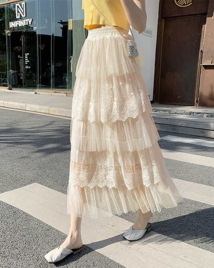 Gonna lunga in tulle a strati con dettagli in pizzo, indossata da una donna su marciapiede urbano. Moda estiva elegante e femminile.