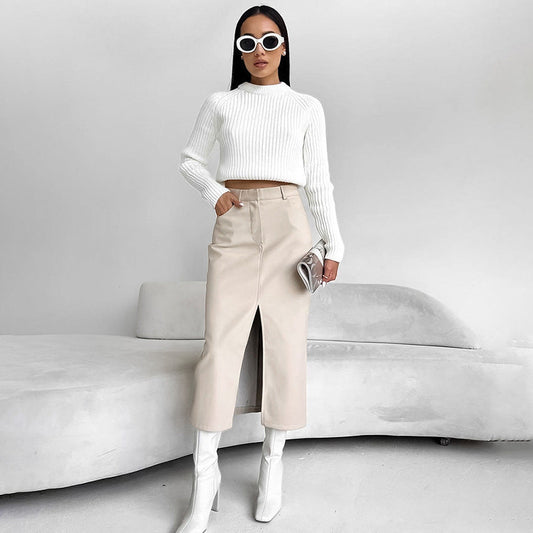 Donna con occhiali da sole bianchi indossa maglione bianco, gonna beige a vita alta e stivali bianchi. Moda minimalista, stile elegante e moderno.