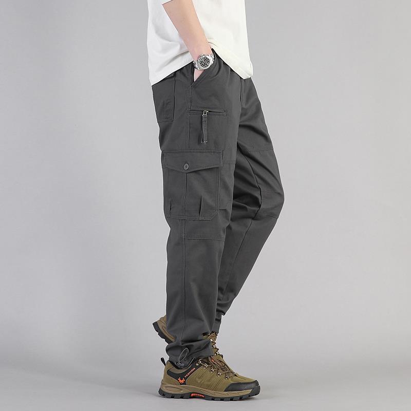 Pantaloni cargo grigi da uomo con tasche multiple, abbinati a scarpe da trekking marroni. Stile casual, moda maschile, abbigliamento outdoor.