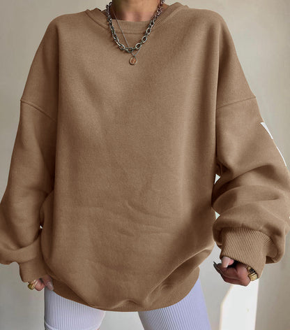Maglione oversize marrone su persona con collana a catena, sfondo neutro. Moda casual autunno, abbigliamento comodo, stile minimalista.
