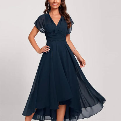 Donna in abito lungo blu scuro elegante, con scollo a V e maniche corte, posa sorridente. Moda femminile, abbigliamento da sera, stile sofisticato.