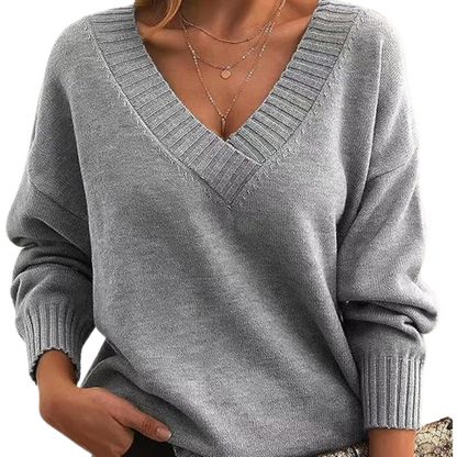 Maglione grigio donna con scollo a V, maniche lunghe, indossato con collane sottili. Stile casual elegante, moda autunno inverno.