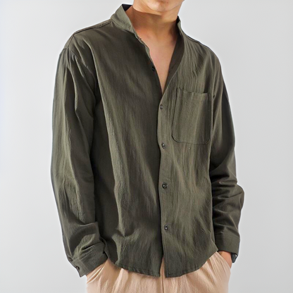 Camicia verde oliva da uomo con colletto alla coreana, maniche lunghe e taschino, abbinata a pantaloni beige. Stile casual ed elegante.