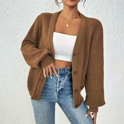 Donna con cardigan marrone a maglia, top bianco corto e jeans. Moda autunnale casual, stile elegante, abbigliamento femminile trendy.