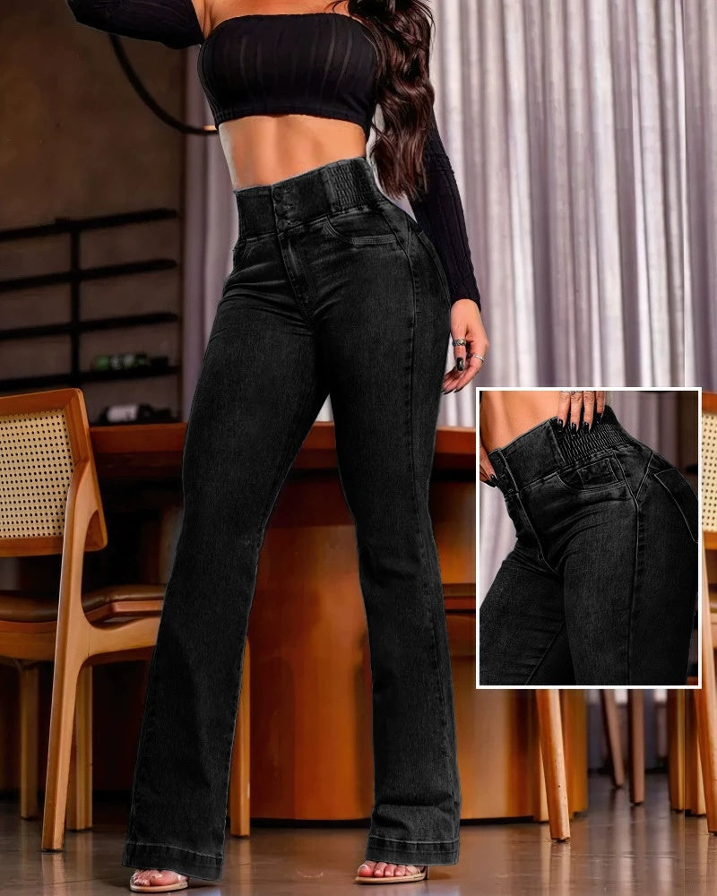 Jeans a vita alta neri, donna in top nero, sedie in legno, ambiente interno moderno. Dettaglio cuciture e design. Moda femminile casual elegante.