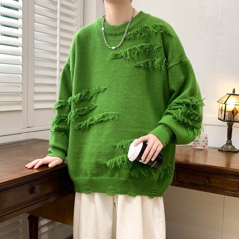 Maglione verde oversize con dettagli sfrangiati, indossato da una persona in un ambiente interno. Stile casual, moda autunnale, tendenza streetwear.