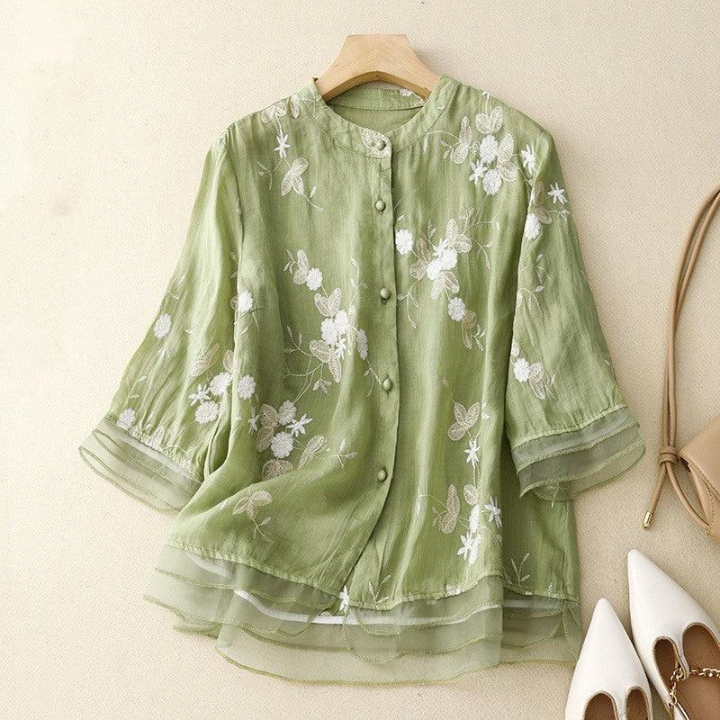 Camicia verde in lino con ricami floreali bianchi, maniche a tre quarti, abbottonatura frontale. Moda donna elegante, abbigliamento estivo.
