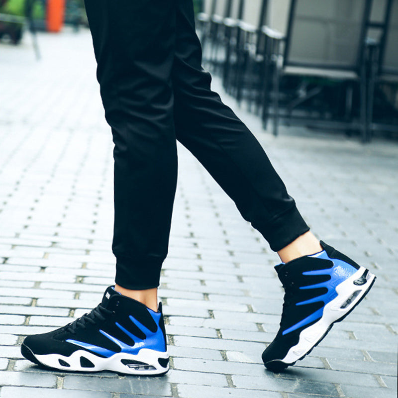 Scarpe da ginnastica nere e blu su pavimento in mattoni grigi, indossate con pantaloni sportivi neri. Sneakers moderne, moda urbana, calzature sportive.