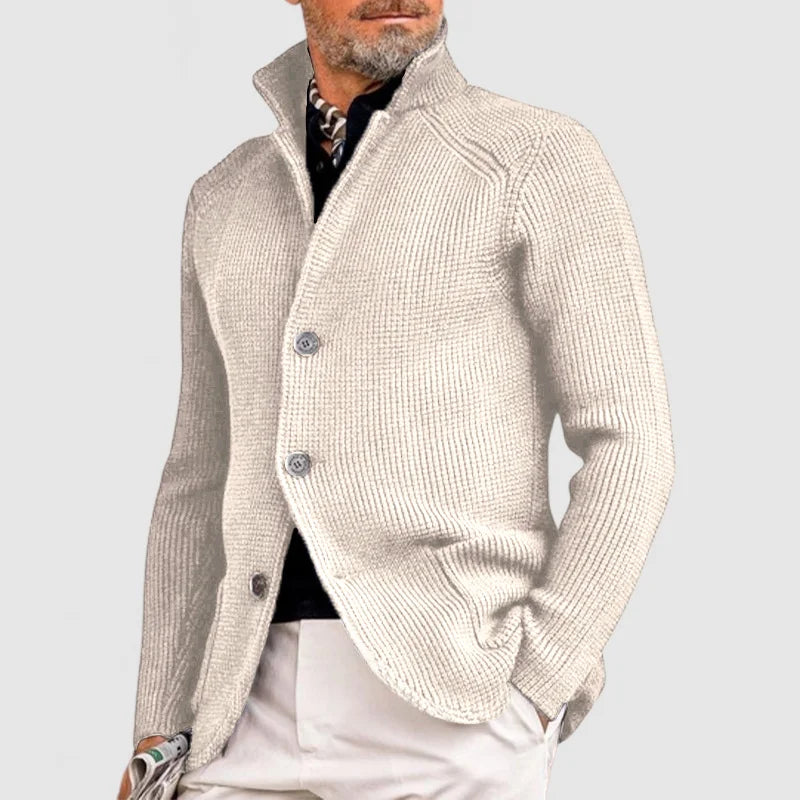 Uomo con cardigan beige elegante, collo alto, abbinato a pantaloni chiari. Moda maschile autunnale, stile casual chic.