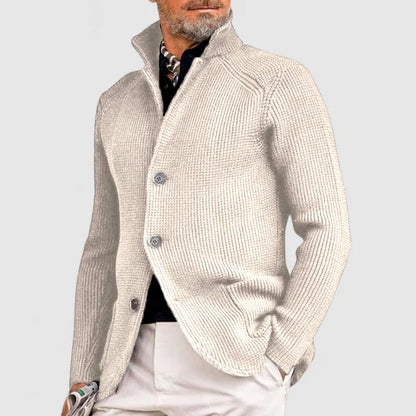 Uomo con cardigan beige elegante, collo alto, abbinato a pantaloni chiari. Moda maschile autunnale, stile casual chic.