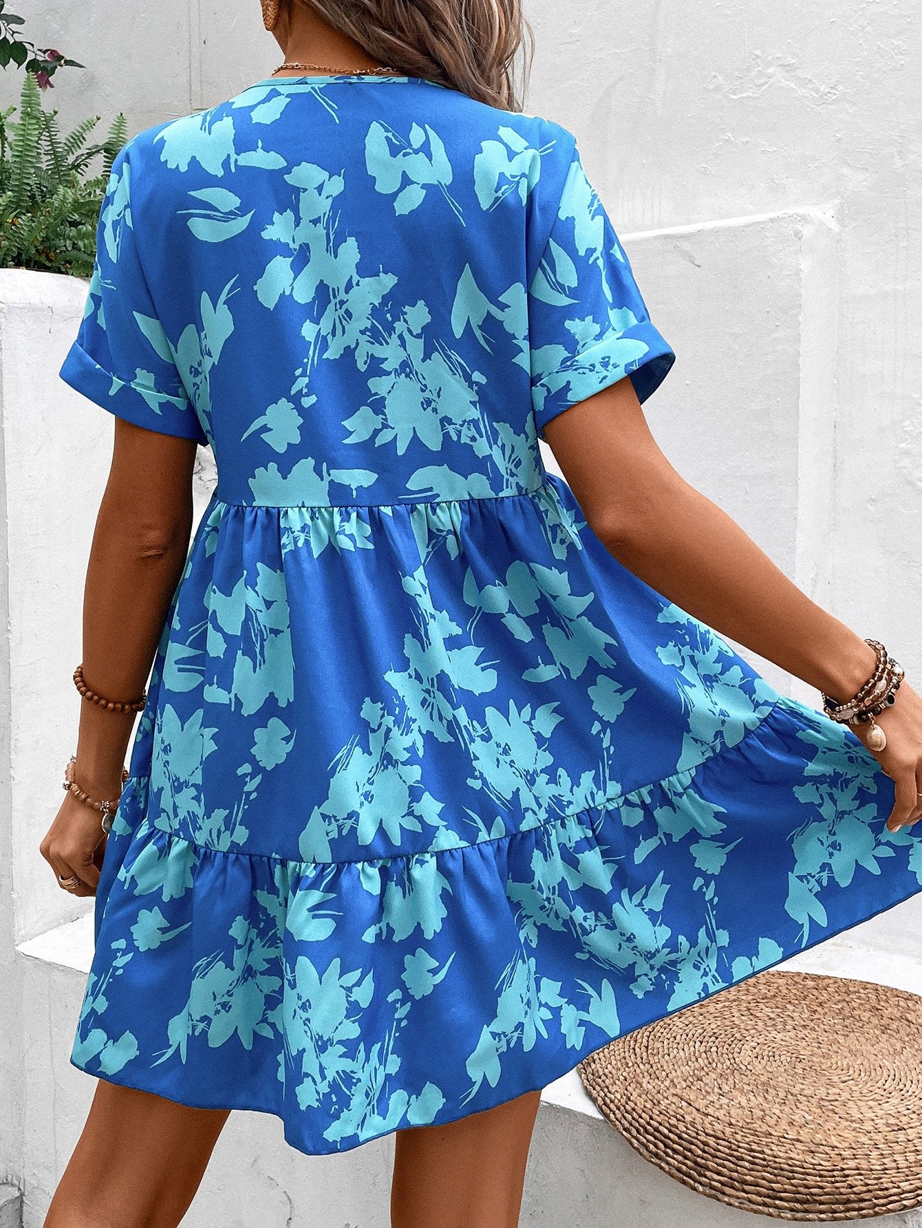 Donna con abito estivo blu a fiori, maniche corte, in posa all'aperto. Moda femminile, abbigliamento casual, stile floreale.