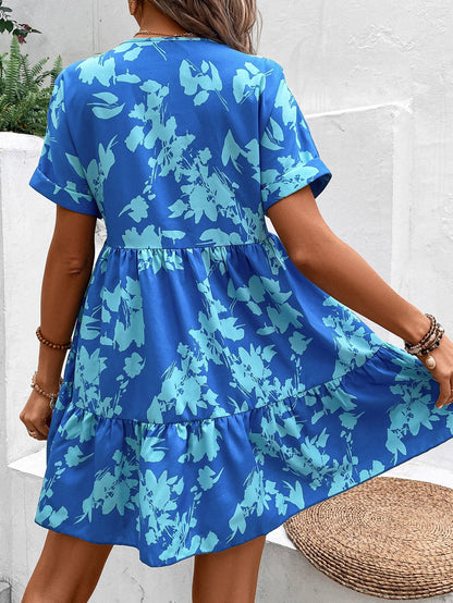 Donna con abito estivo blu a fiori, maniche corte, in posa all'aperto. Moda femminile, abbigliamento casual, stile floreale.