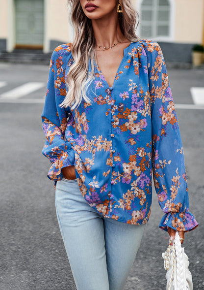 Donna con camicetta floreale blu e jeans chiari, in piedi su strada cittadina. Moda autunnale, abbigliamento casual elegante, tendenze 2023.