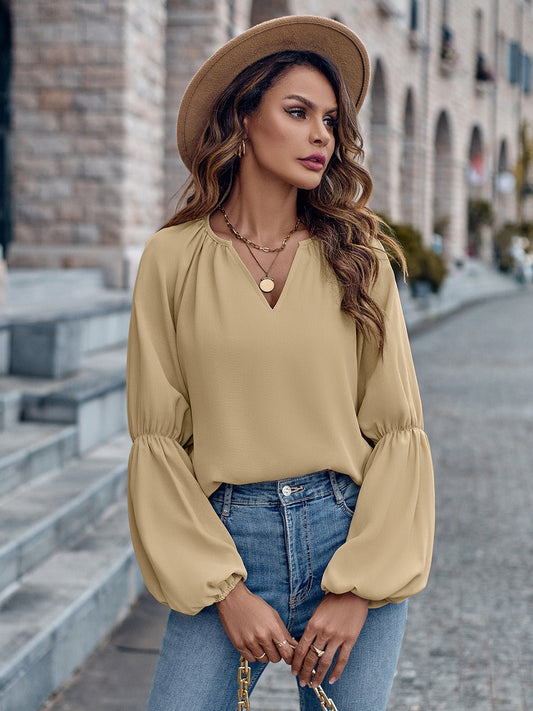 Donna con cappello beige, camicetta gialla a maniche lunghe e jeans, in posa su strada cittadina. Moda autunnale, stile casual chic.