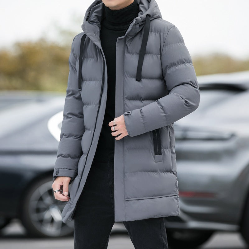 Giacca invernale uomo grigia, imbottita e con cappuccio, indossata su maglione nero. Moda maschile, abbigliamento caldo, stile casual.