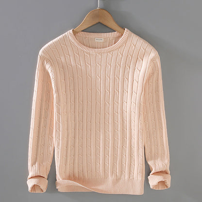 Maglione beige a trecce appeso su gruccia, sfondo grigio. Maglia invernale elegante, moda casual, abbigliamento caldo, stile minimalista.