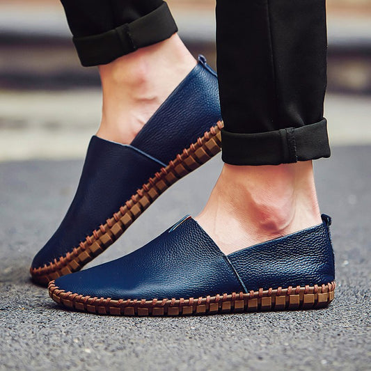 Scarpe mocassini uomo in pelle blu, suola marrone, indossate su strada asfaltata. Calzature eleganti e casual, ideali per moda maschile.