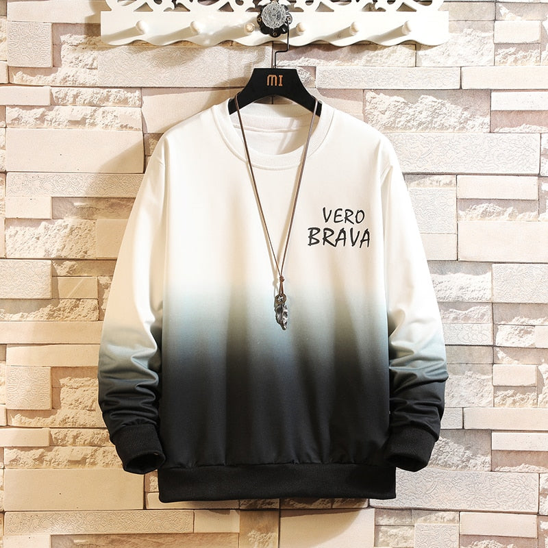Felpa sfumata bianco-nero con scritta "Vero Brava", appesa a un appendiabiti decorativo su sfondo di mattoni. Moda casual, abbigliamento trendy.