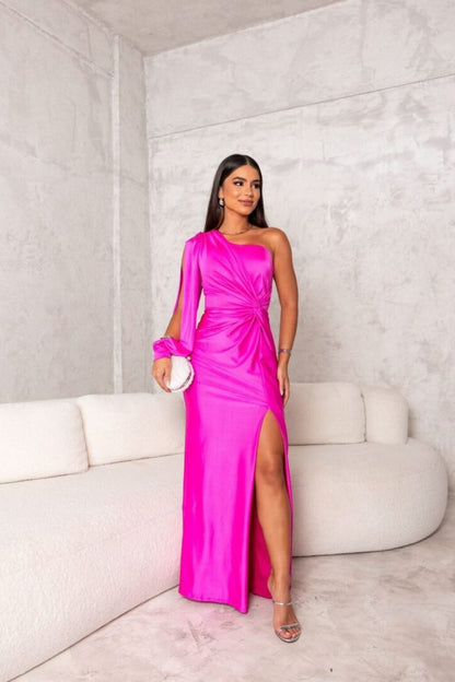 Donna in abito rosa acceso monospalla con spacco, su divano bianco in stanza moderna. Eleganza, moda femminile, abbigliamento da sera.